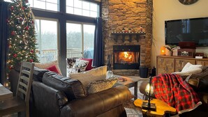 A cozy living room with a stone fireplace, leather sofa, and a Christmas tree. - Fall beauty! Hot tub, Family Friendly, Games Firepit, Pool/Marina Access (Galena)