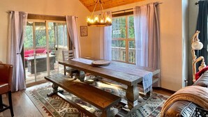 A cozy dining area with a wooden table, benches, and a hanging light fixture. - Fall beauty! Hot tub, Family Friendly, Games Firepit, Pool/Marina Access (Galena)