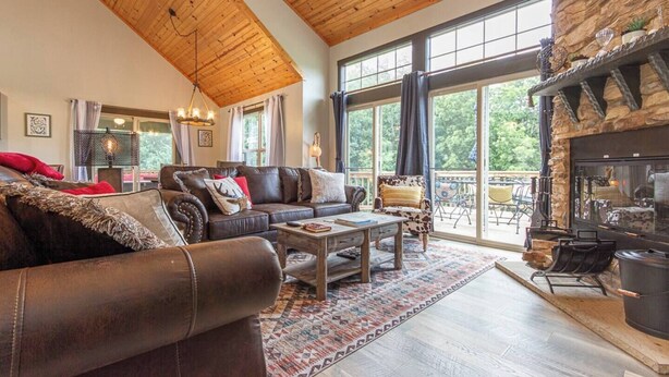 A spacious living room with a leather sofa, a coffee table, and a fireplace. - Fall beauty! Hot tub, Family Friendly, Games Firepit, Pool/Marina Access (Galena)