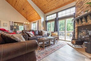 A spacious living room with a leather sofa, a coffee table, and a fireplace. - Fall beauty! Hot tub, Family Friendly, Games Firepit, Pool/Marina Access (Galena)