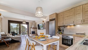 Una cocina moderna con armarios de madera, un comedor con mesa y sillas de madera, un horno empotrado y un ventanal con vistas.