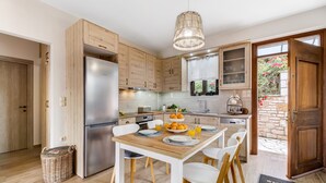 Una cocina moderna con armarios de madera, un refrigerador de acero inoxidable, una mesa de comedor con sillas y una cesta de mimbre en el suelo.
