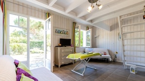 A room with a bed, a television, a desk, and a window with a view of greenery.