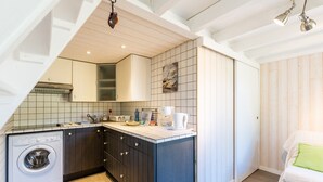A compact kitchen with a built-in washing machine, a coffee maker, and a sink.