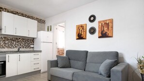 Een moderne keuken met witte kasten, een grijze bank en wanddecoratie.