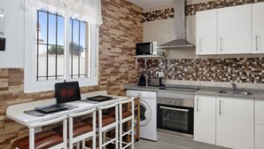 Een keuken met een wasmachine, magnetron, oven en een raam met uitzicht.