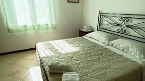 A bedroom with a bed, a nightstand, a picture on the wall, and a window with curtains. - Holiday Home 'Tramonto sul Castello di Poppi' with View, Hot Tub, Garden & Wi-Fi (Poppi)