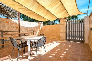 A patio with a table and chairs, a stone wall, and a gated entrance.