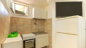 A compact kitchen with a stove, oven, sink, and a flat-screen TV mounted above the refrigerator. - Pet-Friendly Apartment Acquadolce with Sea View & Terrace (marina di maruggio)
