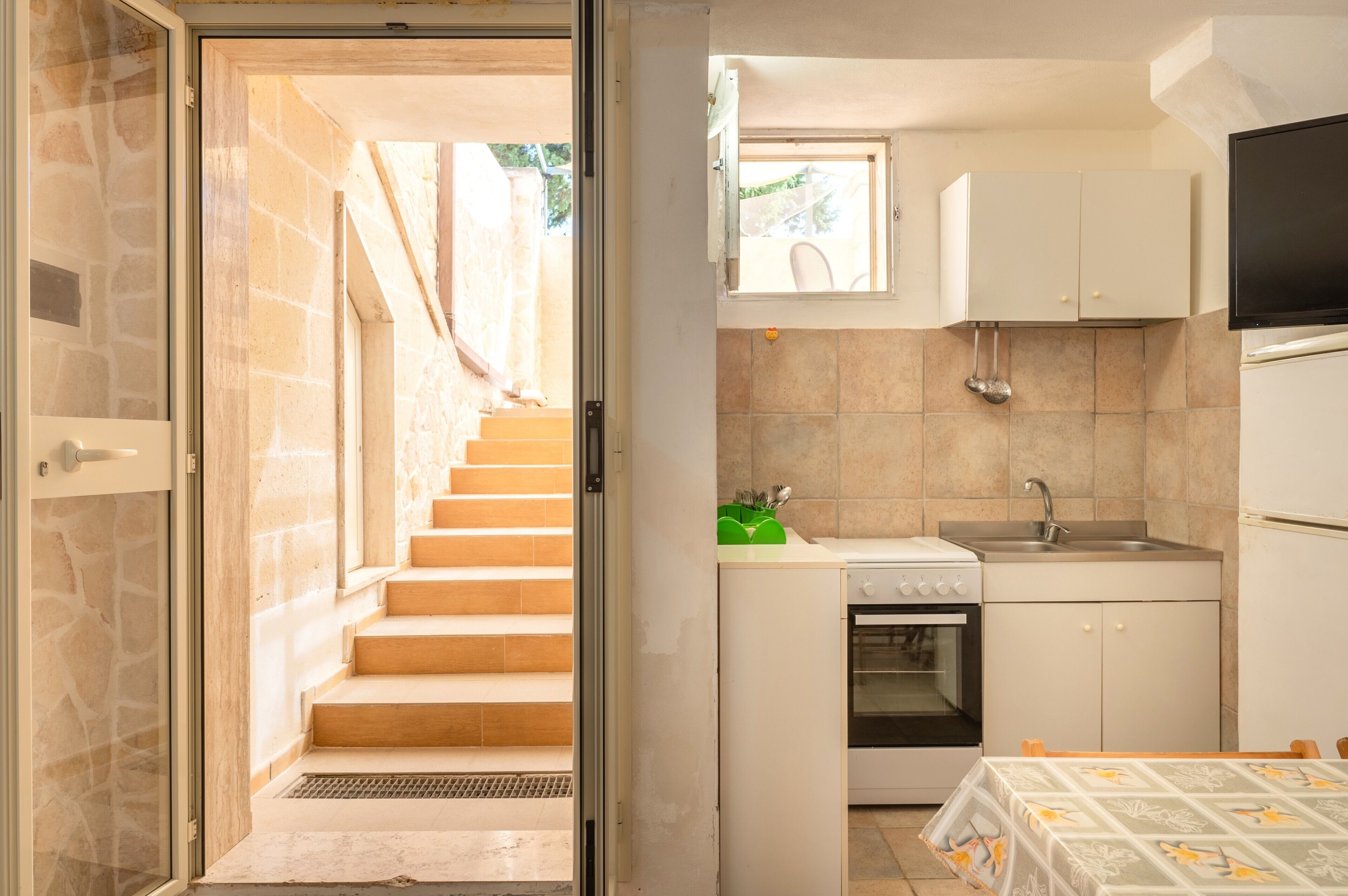 A compact kitchen with a built-in oven, a sink, and a window above the countertop.