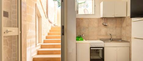 A compact kitchen with a built-in oven, a sink, and a window above the countertop.