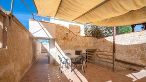 A patio with a table and chairs, stone walls, and a wooden railing. - Pet-Friendly Apartment Acquadolce with Sea View & Terrace (marina di maruggio)
