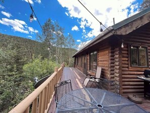 Une cabane en bois avec une terrasse, une table en métal et des chaises.
