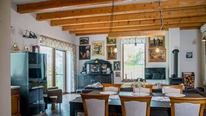 A cozy dining area with wooden chairs and a table, a black cabinet with glass doors, and a fireplace. - Captivating 3-bedrooms Cottage in the Hills (Uhliská)