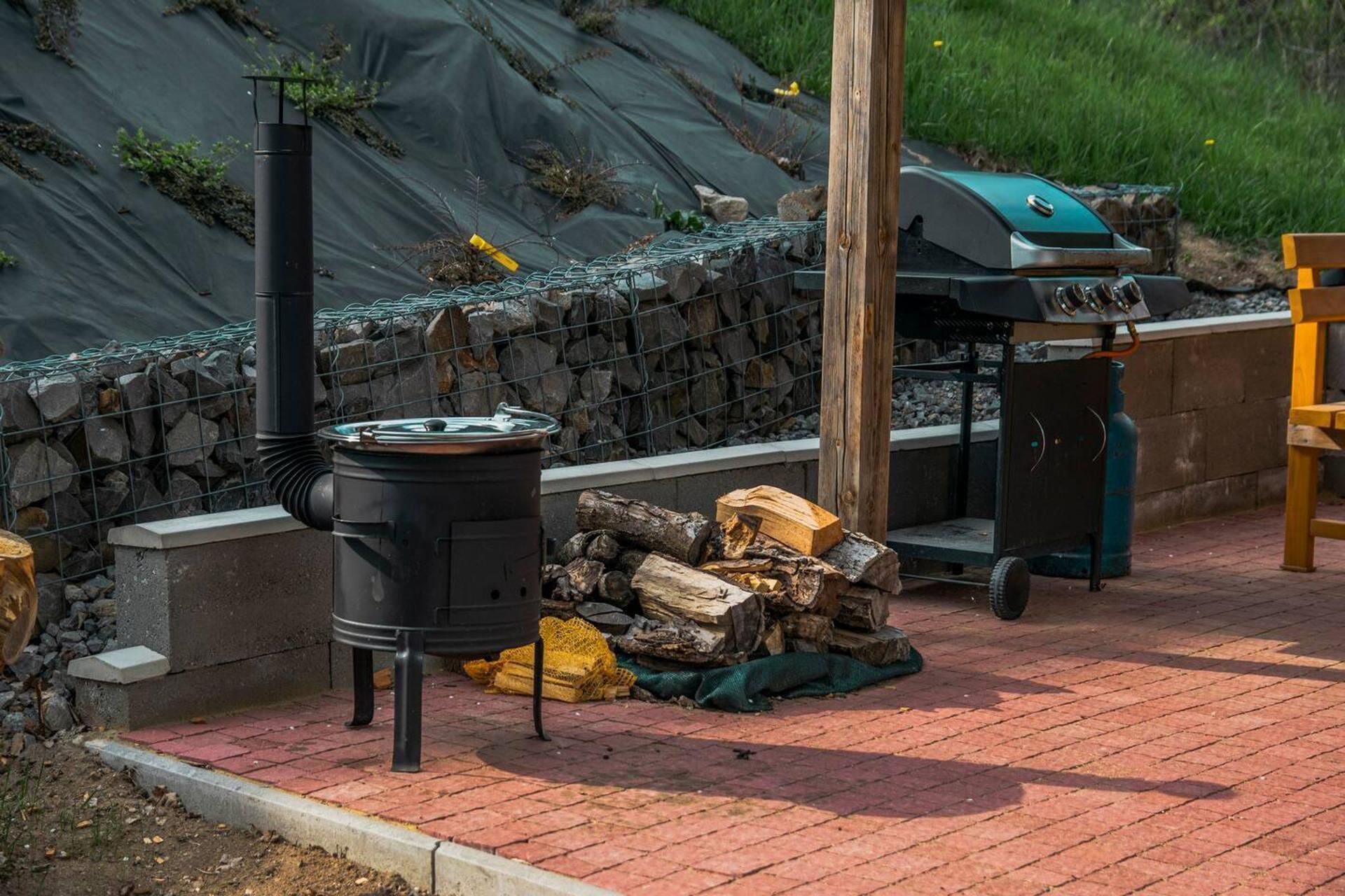 Una parrilla portátil y un estufa de leña en un patio de ladrillo.