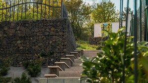 A stone wall with a metal fence, concrete steps, and greenery. - Captivating 3-bedrooms Cottage in the Hills (Uhliská)