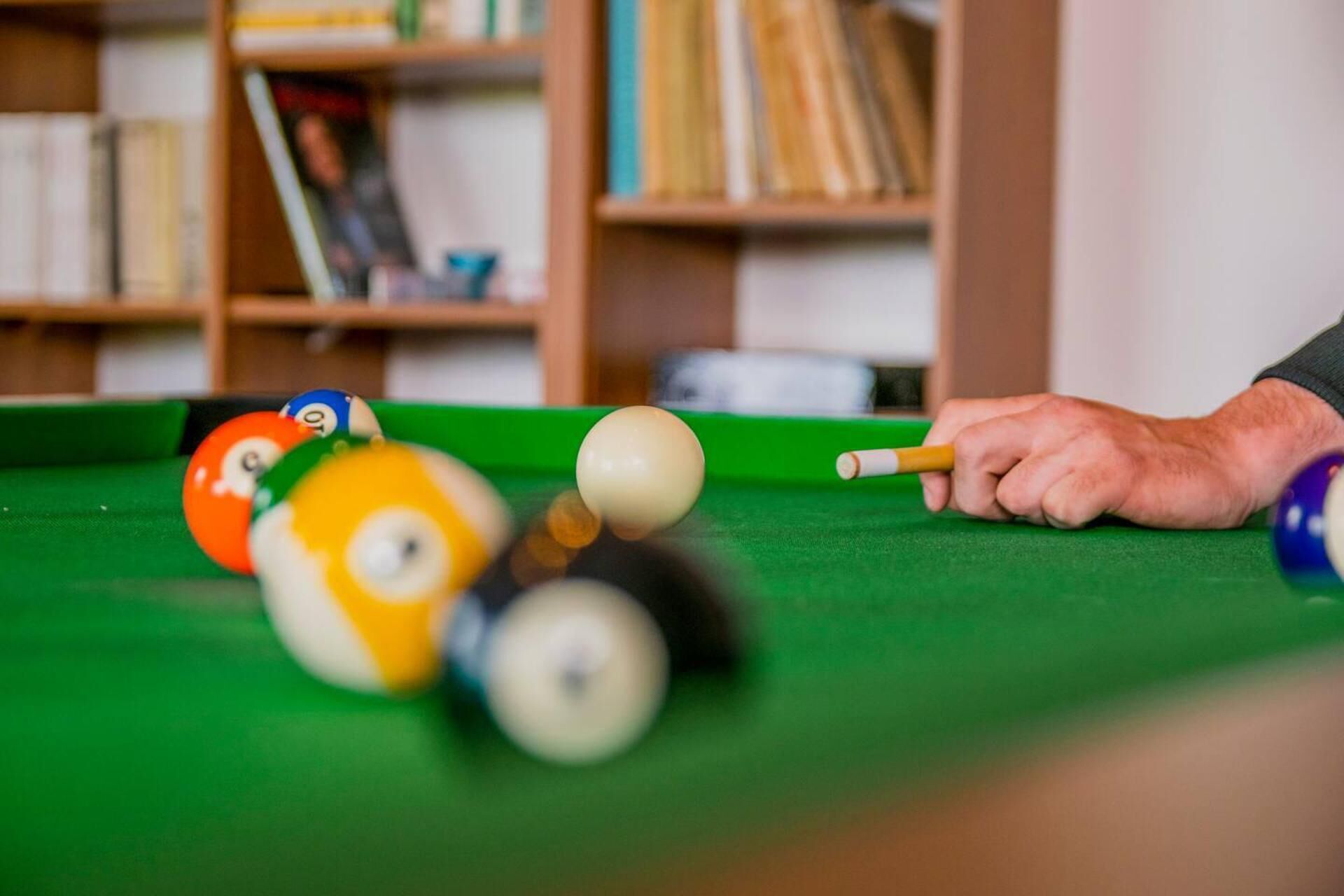 A close-up of a pool table with a cue stick and billiard balls.