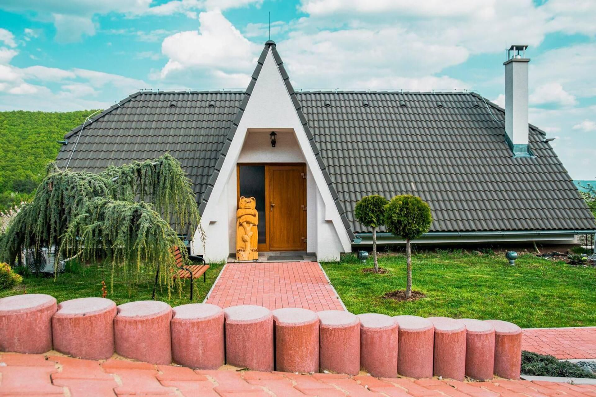 Een huis met een puntig dak, een houten deur en een schoorsteen.