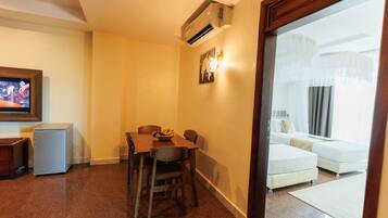 A hotel room with a dining area, a small refrigerator, a bed, and a television.