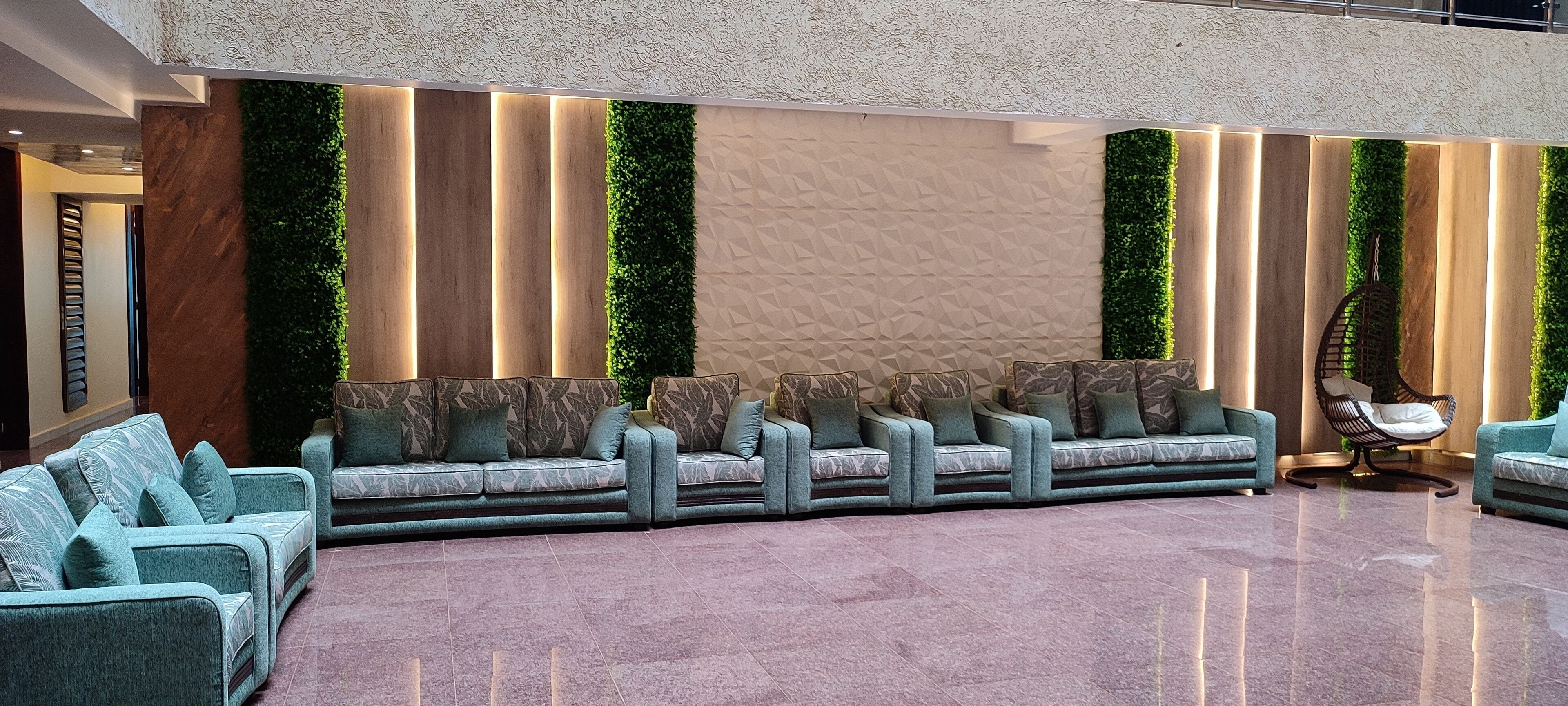 Een moderne lobby met een lange bank, een hangstoel en een gestructureerde wand.