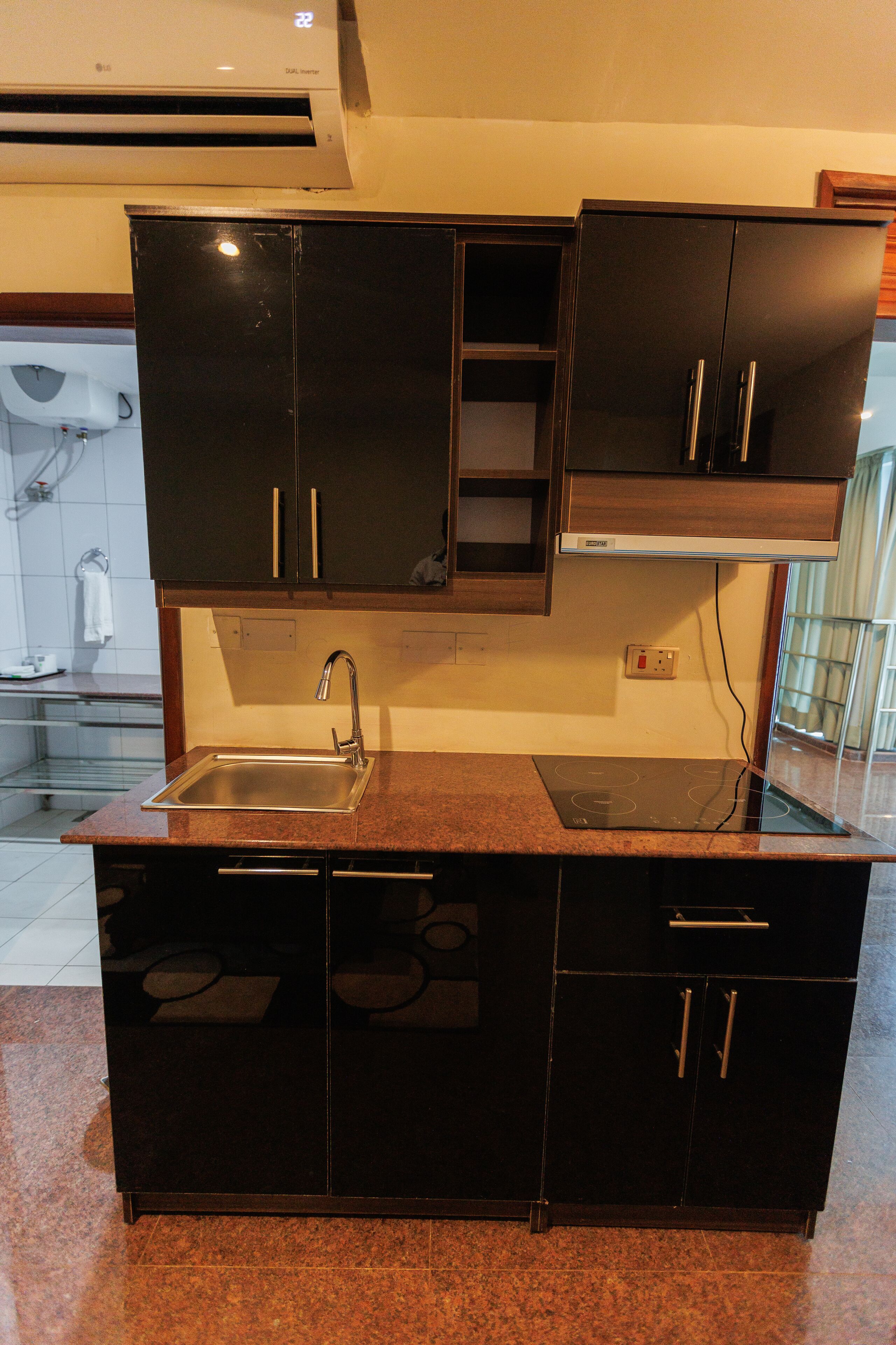 Una cocina con pileta de acero inoxidable, gabinetes negros y horno integrado.