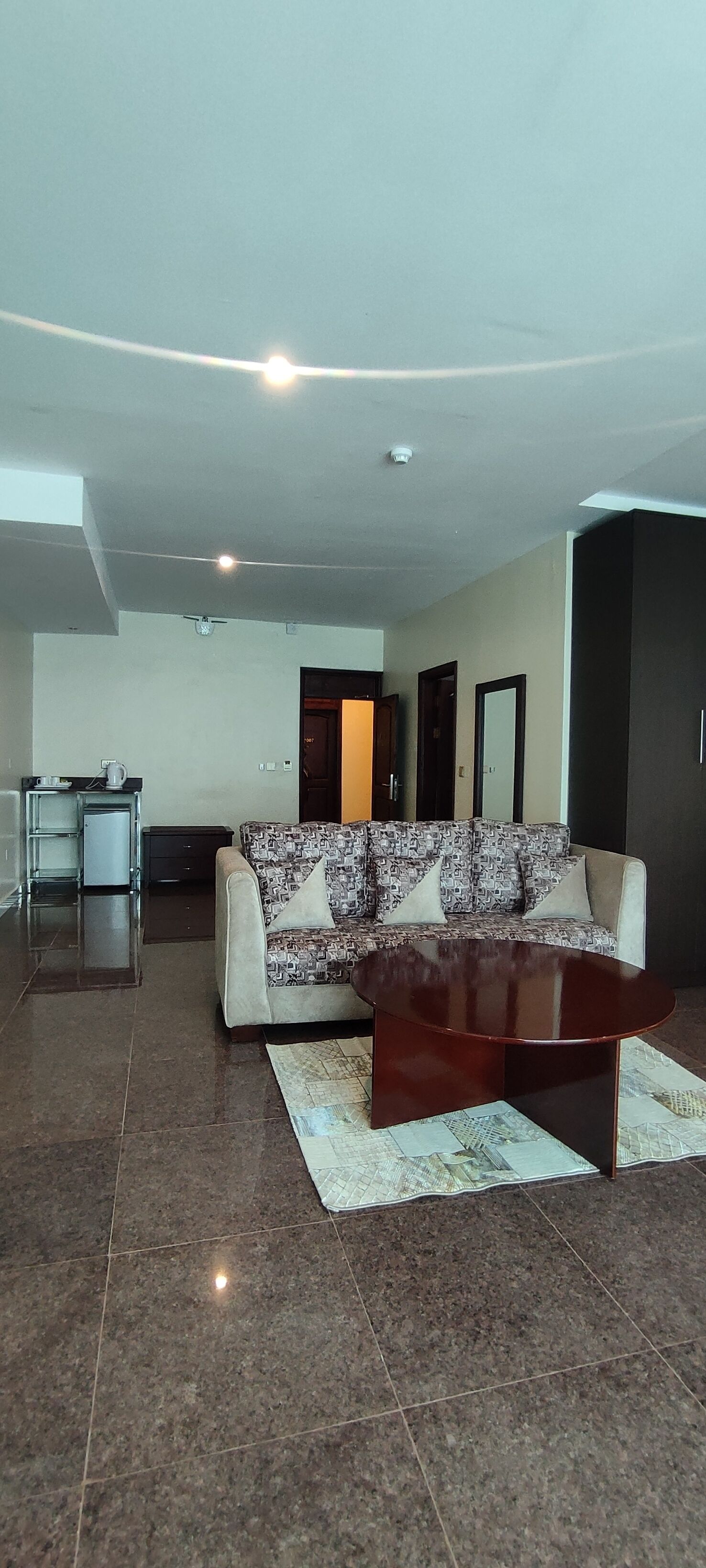 A modern living room with a sofa, coffee table, and a small kitchenette.