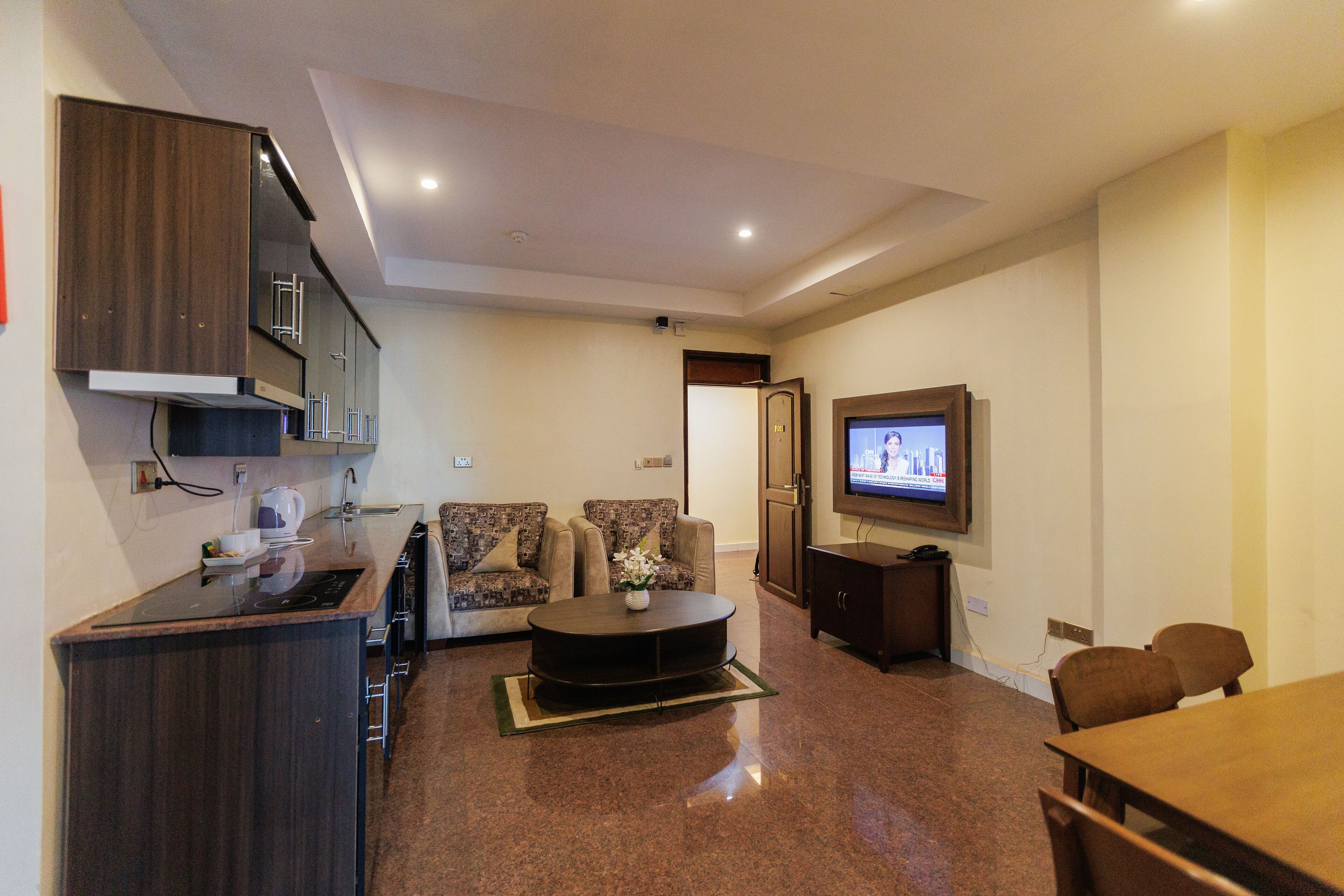 Un espacio habitable compacto con kitchenette, un sofá, una mesa de centro y una televisión.