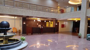 Un hall d’entrée spacieux avec un comptoir d’accueil, une fontaine et un balcon situé au deuxième étage.