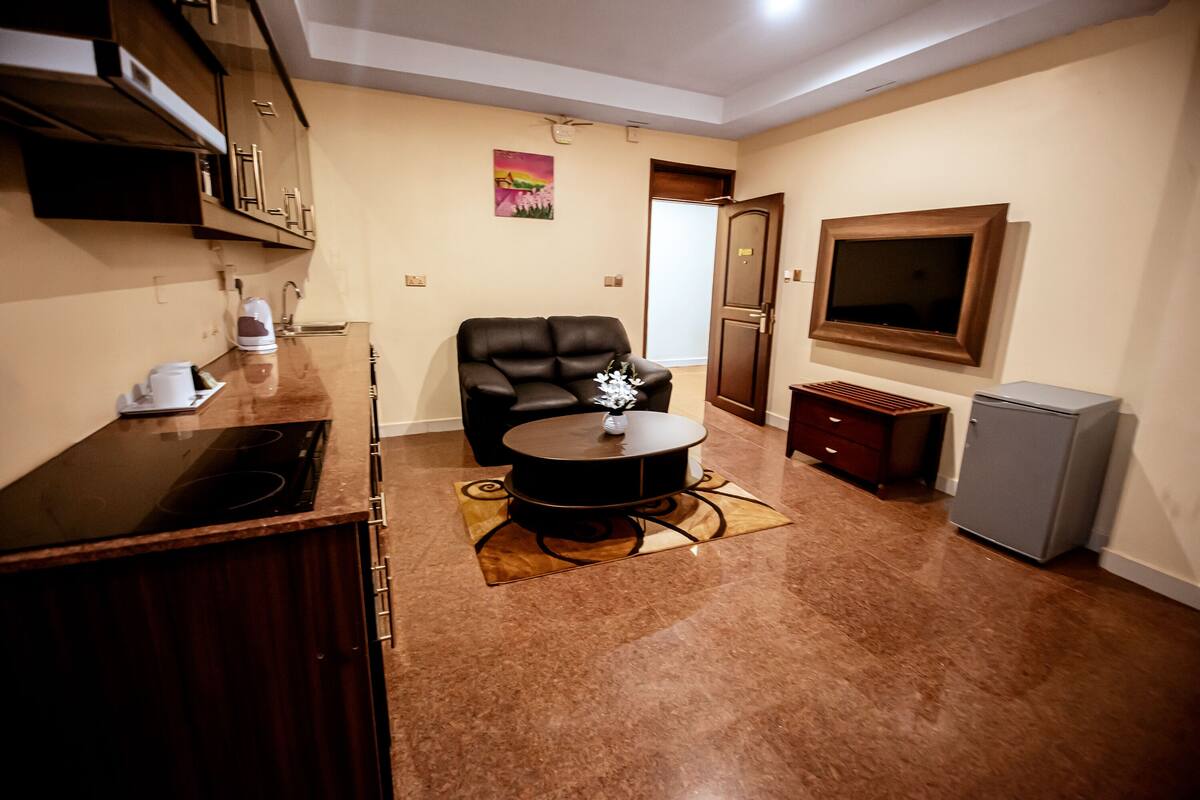 Un espacio habitable compacto con una zona de cocina, una mesa de comedor, un sofá y un televisor montado en la pared.