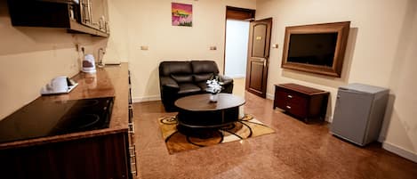 A compact living space with a kitchen area, a dining table, a sofa, and a TV mounted on the wall.