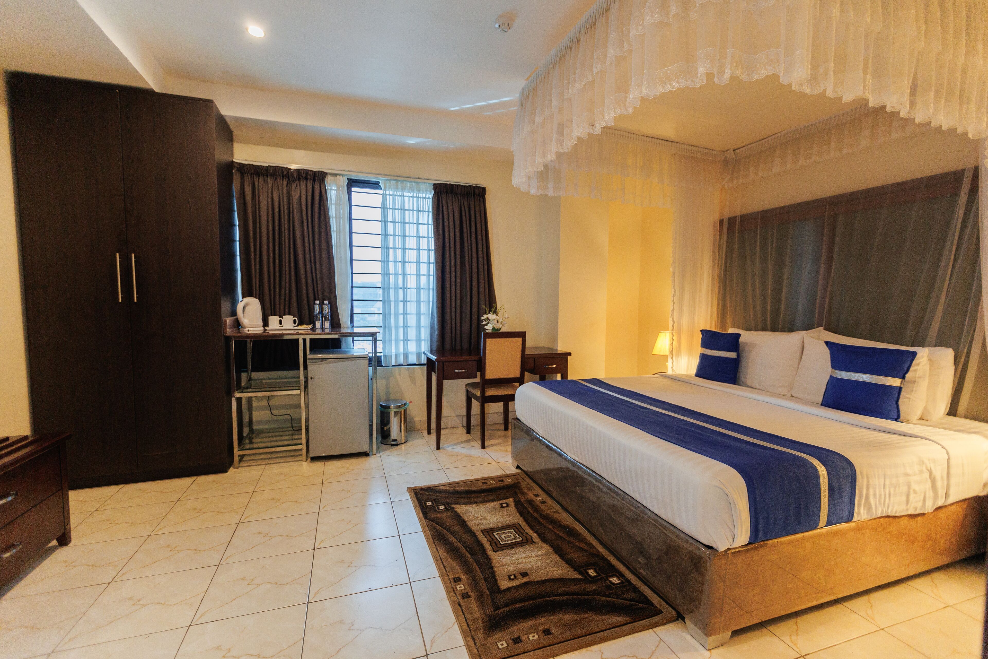 A hotel room with a bed, a desk, a wardrobe, and a small kitchenette.