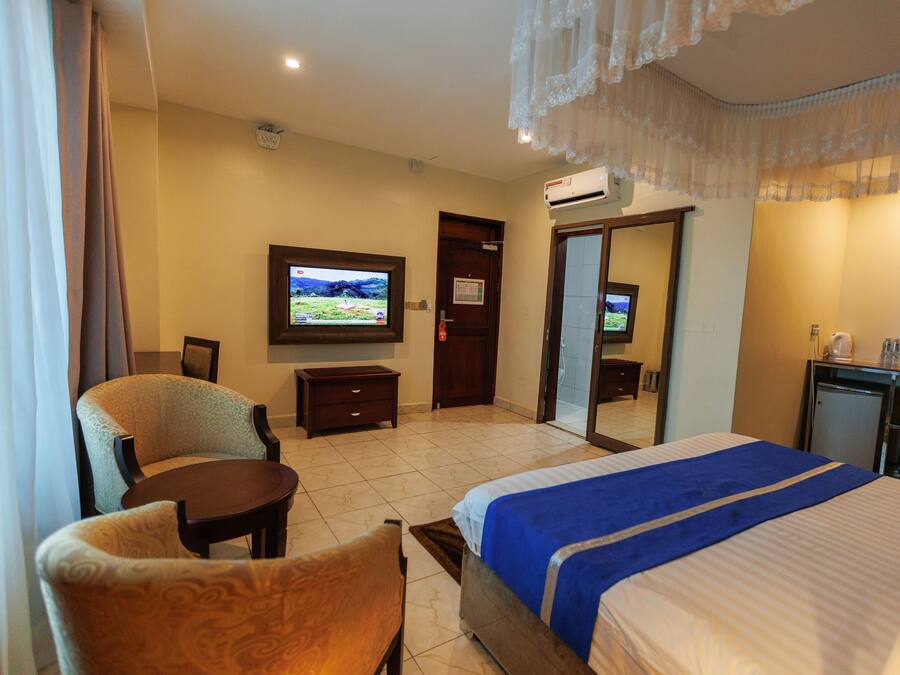 Ein Hotelzimmer mit einem Bett, einem Fernseher, einem Schreibtisch und einem Sessel.