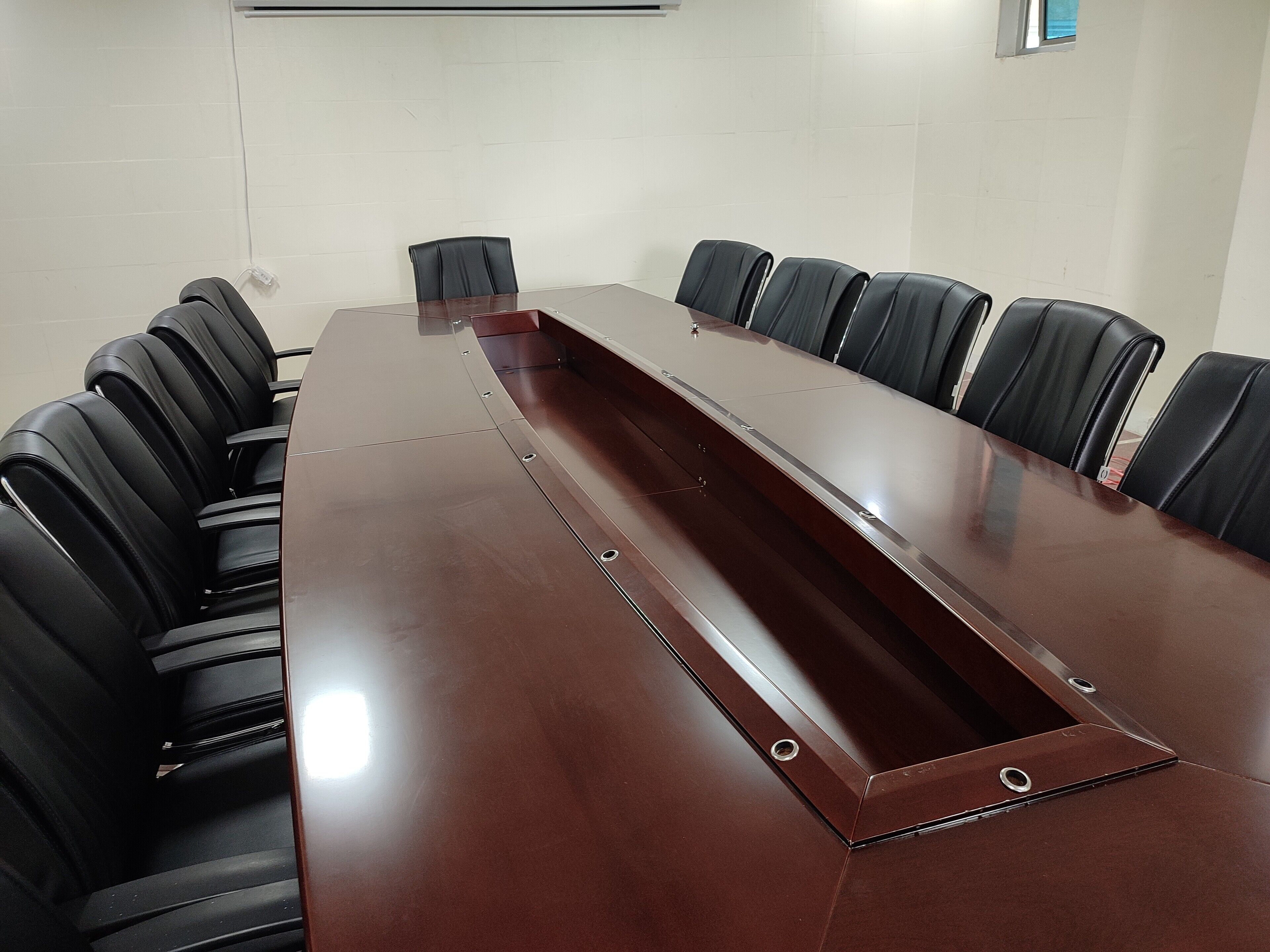 A conference room with a long rectangular table and black leather chairs.