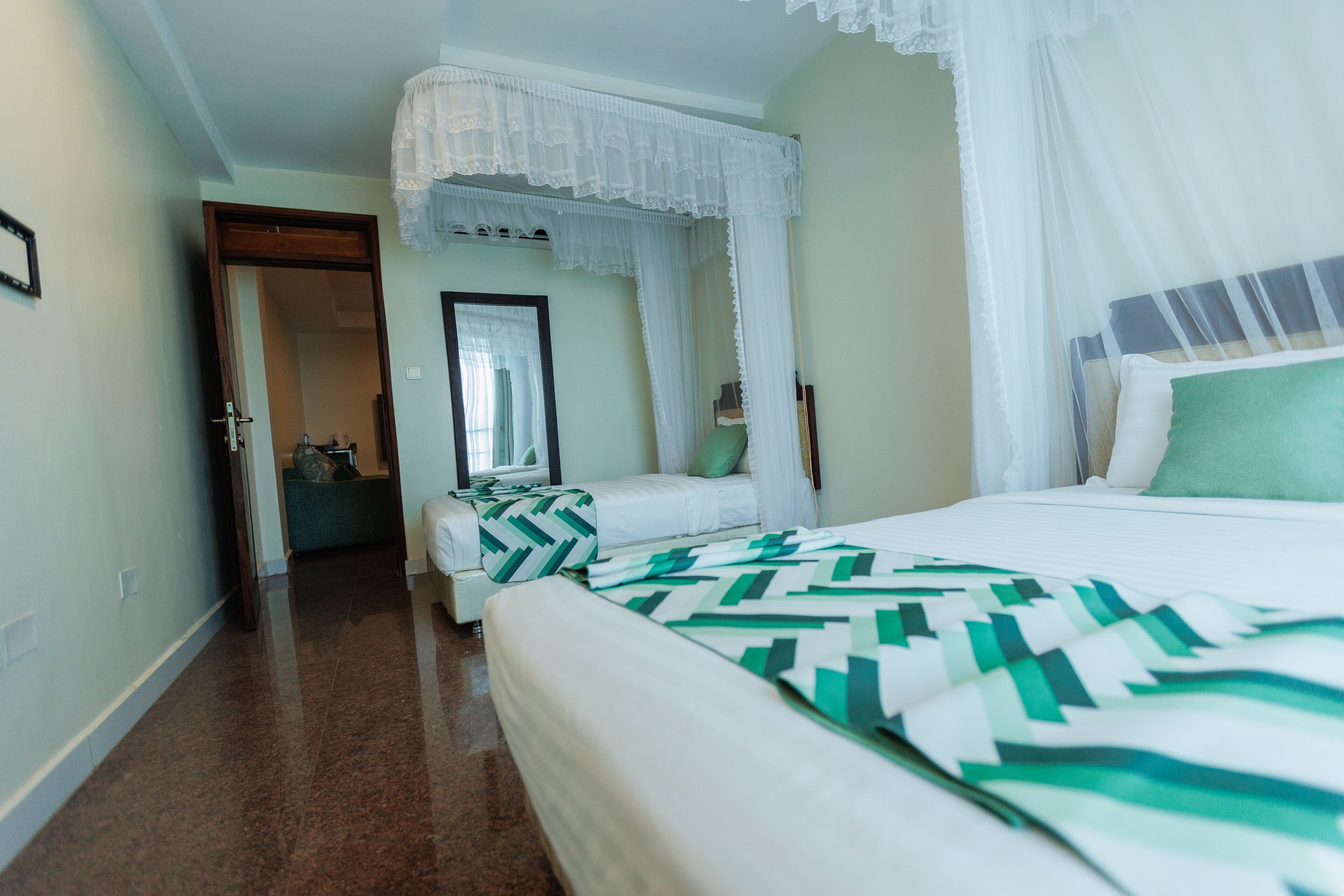 A hotel room with a large bed, a smaller bed, and a sitting area.