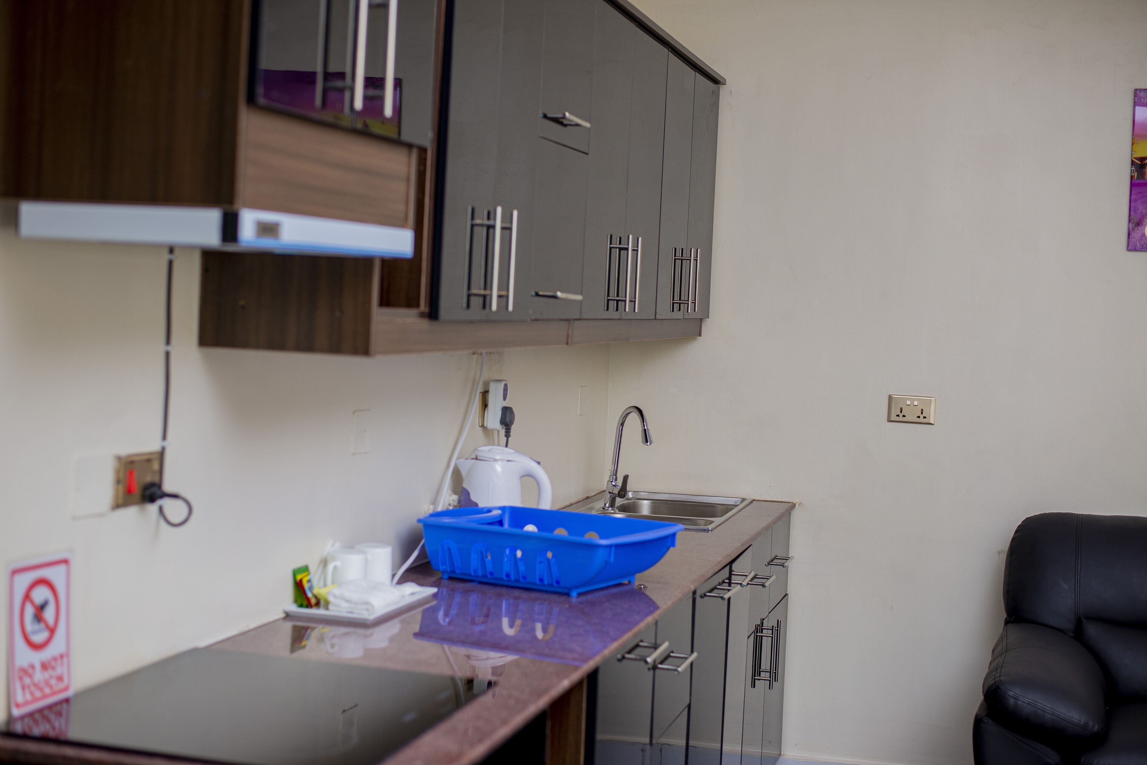 A compact kitchen with a sink, cabinets, and a blue tray on the counter.
