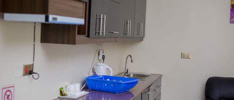 A compact kitchen with a sink, cabinets, and a blue tray on the counter.