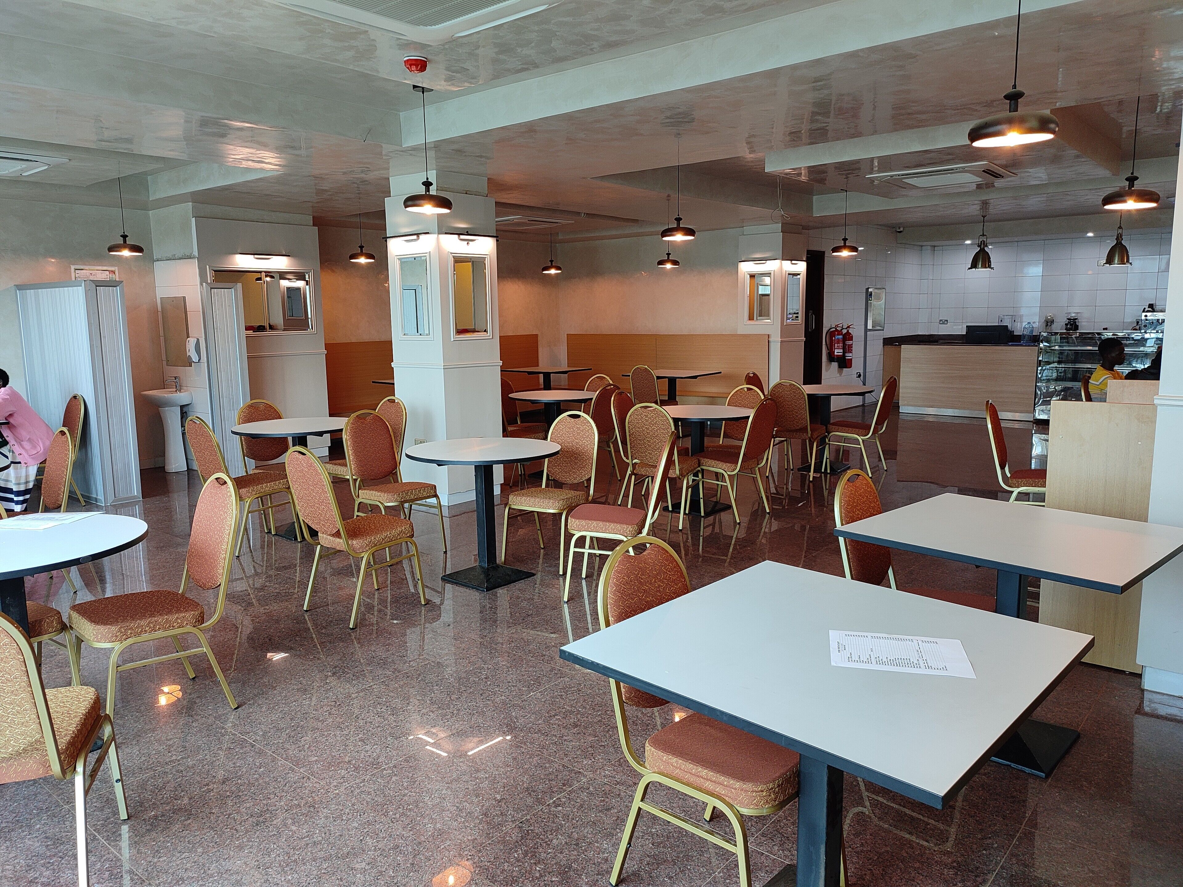 A dining area with tables and chairs, a sink, and a fire extinguisher.