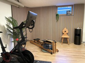 A home gym with an exercise bike, a rowing machine, and a small wooden table. - Country house Obermaiselstein THE VIEW - wonderful mountain view from apartment Besler (Obermaiselstein)