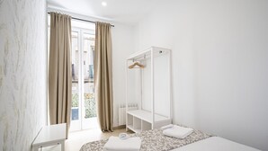 Una habitación de hotel con cama, armario, espejo y ventana con cortinas.