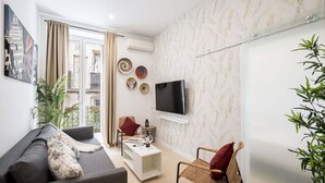 Una sala moderna con un sofá, una mesa de centro, un televisor y una silla.