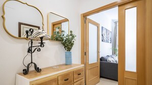 Una habitación con un aparador de madera, un espejo, una lámpara y un florero con una planta.