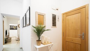 A hallway with a wooden door, a white wall, and a small table with candles and a plant.