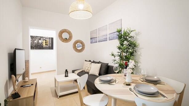 A modern living room with a sofa, dining table, and a large window.