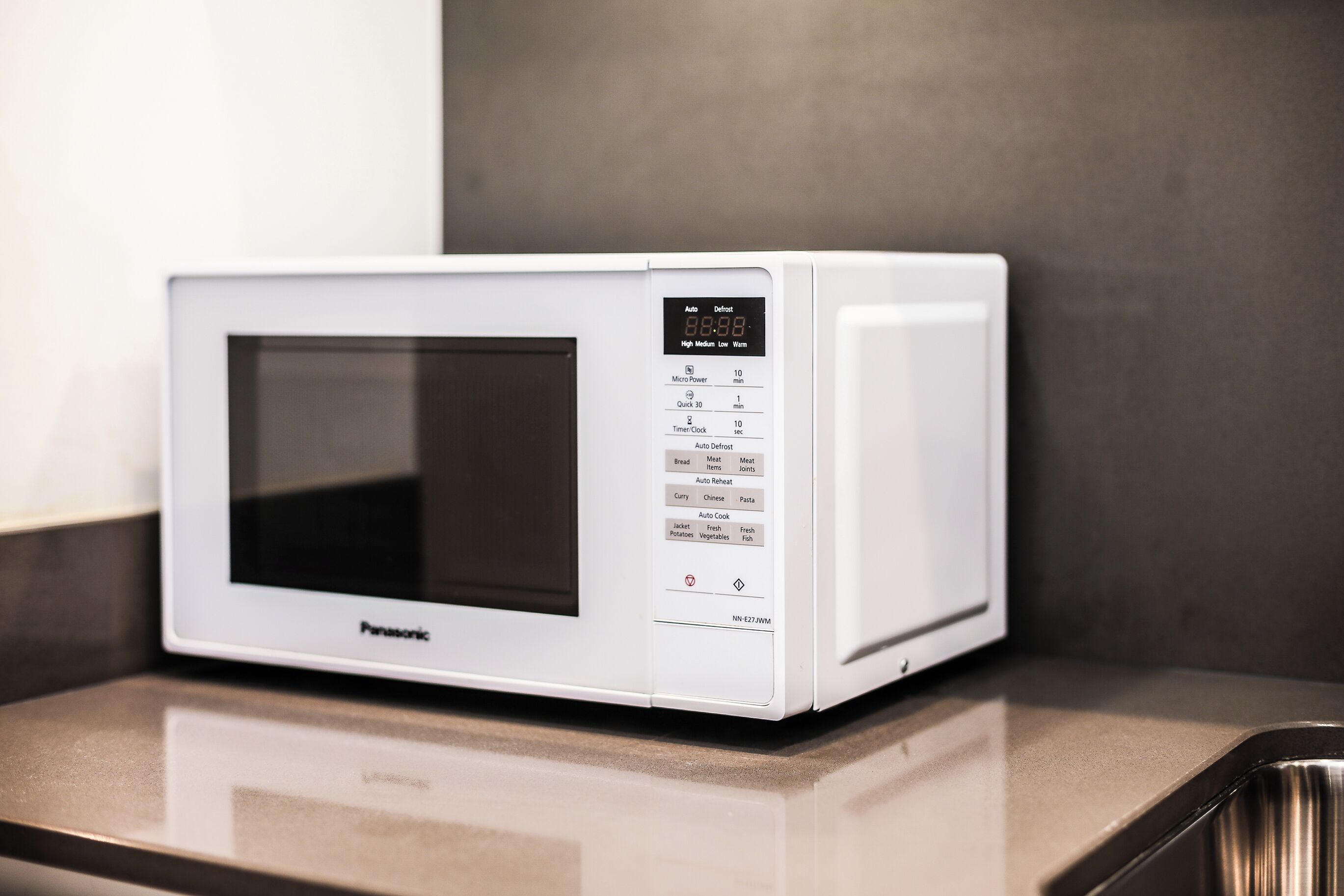 Un forno a microonde Panasonic bianco con display digitale e diversi pulsanti preimpostati sul lato destro.