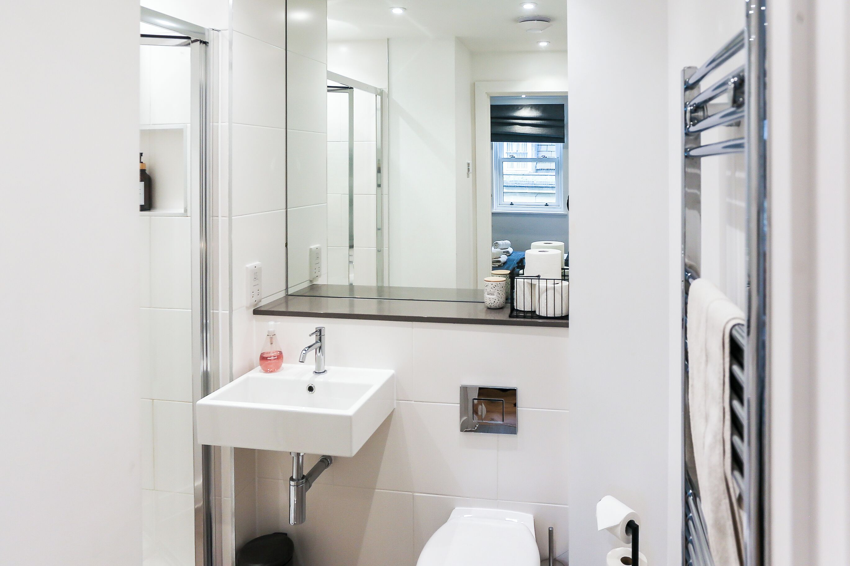 Une salle de bain moderne avec un lavabo blanc, un miroir et un porte-serviettes.