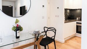A modern kitchen with white cabinets, a black countertop, and a built-in oven. - Chapel - Central Studio Apartment (Bath)