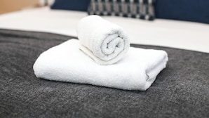 A neatly folded white towel on a grey bedspread in a hotel room. - Chapel - Central Studio Apartment (Bath)