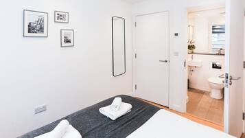 Una camera d'albergo con un letto, due asciugamani, un grande specchio e tre quadri appesi al muro.