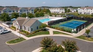 Et boligområde med swimmingpool, tennisbaner og parkeringsplads.