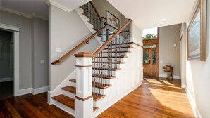 A staircase with wooden steps and a white handrail, leading to a landing with a door. - MINNeSTAY* Dean Parkway Estate Luxury | Spacious (Minneapolis)